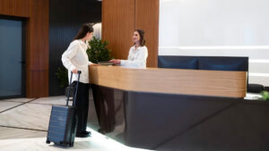 A woman with a suitcase receiving assistance at the hotel reception