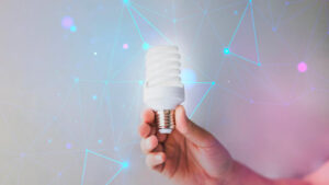 Individual holding a light bulb amidst a backdrop of interconnected technological network elements